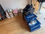 several pairs of shoes are stacked on top of boxes on the floor