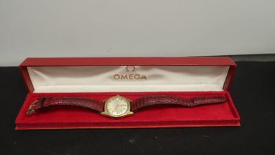 une montre Omega dans un coffret rouge posé sur une surface noire