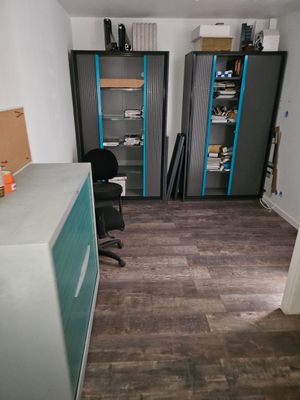 a room with a desk, shelves and a chair in it
