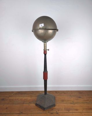 une image représentant une boule métallique posée sur un socle, sur un plancher en bois