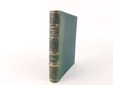 an old book sitting on top of a white table next to a white wall