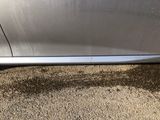the side of a silver car with the door handle missing