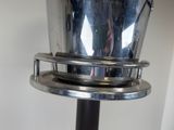 someone is taking a picture of a silver vase on a metal stand