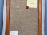 an old picture frame with a red button in it on a blue wall