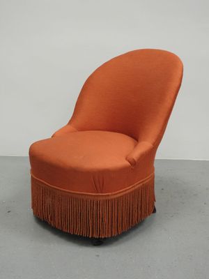 une chaise orange ornée de franges dans une pièce