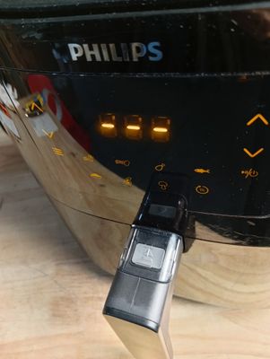 un gros plan d'un téléphone portable branché à une friteuse à air chaud