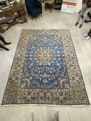 Plusieurs personnes sont debout autour d'un grand tapis dans une pièce.