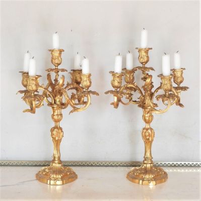 deux chandeliers en or posés sur une table en marbre