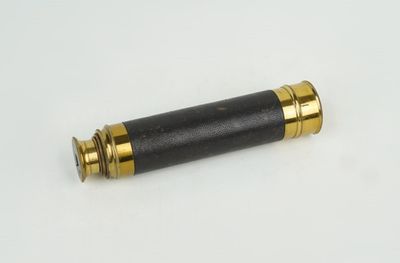 un gros plan d'un télescope noir et doré posé sur une surface blanche