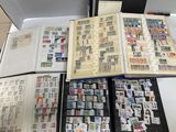 de nombreux timbres posés sur une table, à côté d'un livre ouvert