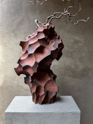 une sculpture abstraite représentant un arbre, posée sur un socle devant un mur
