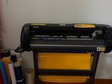 une machine posée par terre à côté de quelques rouleaux de papier