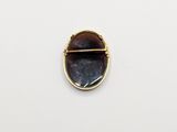 a close up of a gold plated broochle with a black stone