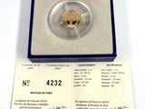 a gold coin in a blue box with a red label