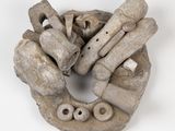 une sculpture en argile et en bois posée sur un fond blanc