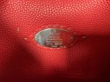 a close up of a red purse with a metal tag on it