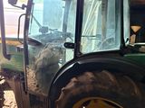 a tractor that is parked in a barn with hay on the ground
