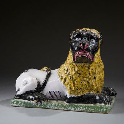 a ceramic sculpture of a lion laying down on the ground