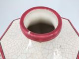 a red and white vase sitting on a white table