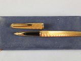 a gold pen and a black pen sitting on a blue cloth