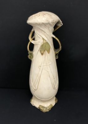 a white vase with a green leaf decoration on it