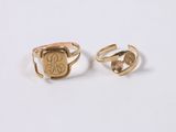a pair of gold rings with initials on them on a white surface