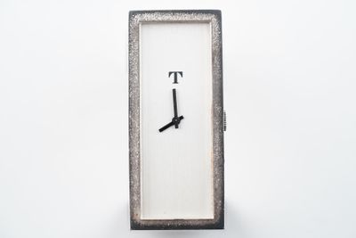 une horloge portant la lettre t sur une surface blanche