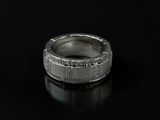 a close up of a silver ring with diamonds on a black surface