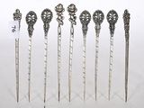 six cuillères en argent ornées de motifs élaborés, posées sur une surface blanche