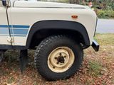 a white truck with a blue stripe parked on the side of the road