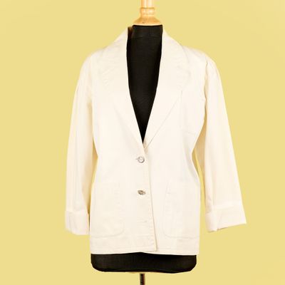 une veste blanche posée sur un mannequin, devant un fond jaune