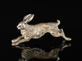 a silver rabbit figurine sitting on top of a black surface