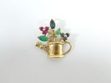 une broche plaquée or représentant des fleurs et un arrosoir