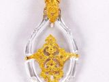 a close up of a gold and clear glass pendant on a white surface