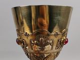 a gold goblet with a red bead on it