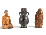 trois petites statues de bouddhas assis les uns à côté des autres sur une surface blanche