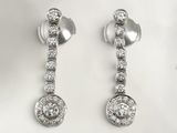 two pairs of diamond earrings on a white surface