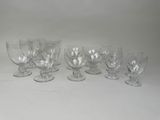 six verres à vin transparents alignés sur une surface blanche