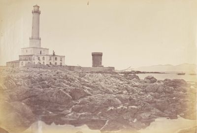 une photo en noir et blanc d'un phare sur un rivage rocheux