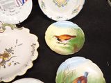 many plates with birds painted on them sitting on a table