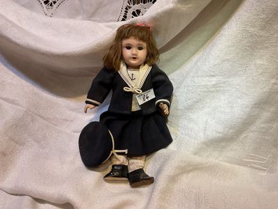 une petite poupée assise sur un drap blanc