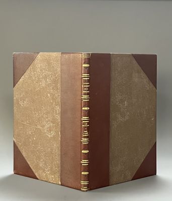 an old book with a brown cover sitting on top of a white table