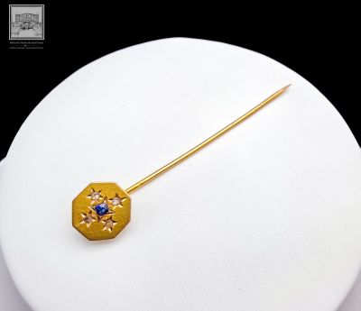 une broche en or ornée d'une pierre bleue au centre