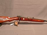 un vieux fusil avec un canon en bois sur un support sur fond blanc