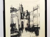 dessin représentant un paysage urbain, dans un cadre noir et blanc, posé sur un chevalet en bois