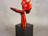 sculpture of a red face on a black base on a white background