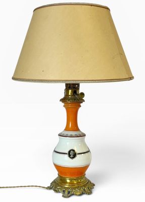 une lampe orange et blanche posée sur une table, à côté d'un abat-jour