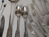 a lot of silver spoons and forks on the table