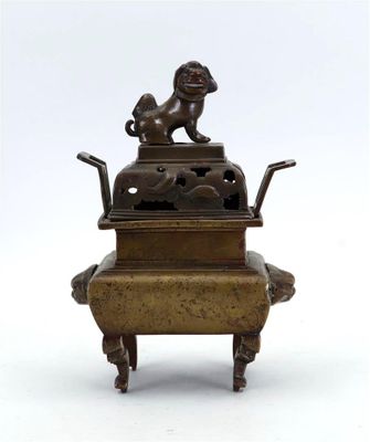 une statue en bronze représentant un chien assis sur une boîte