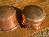 deux vieilles casseroles en cuivre posées sur une table en bois